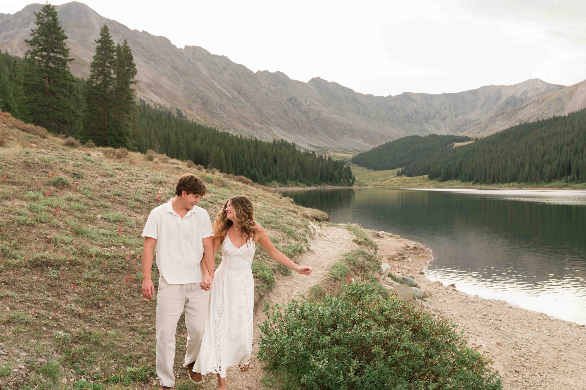 Brock and Anna walking hand in hand along the lake trail